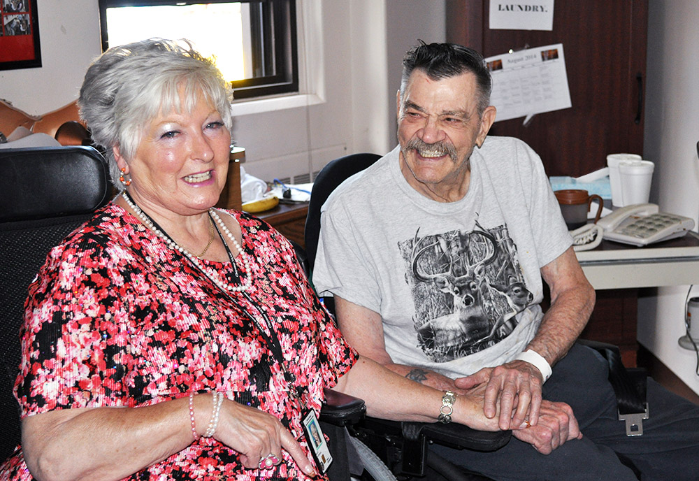 elderly female volunteer sitting beside an elderly male patient