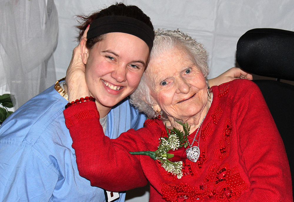 Elderly woman in a wheelchair hugs a young woman