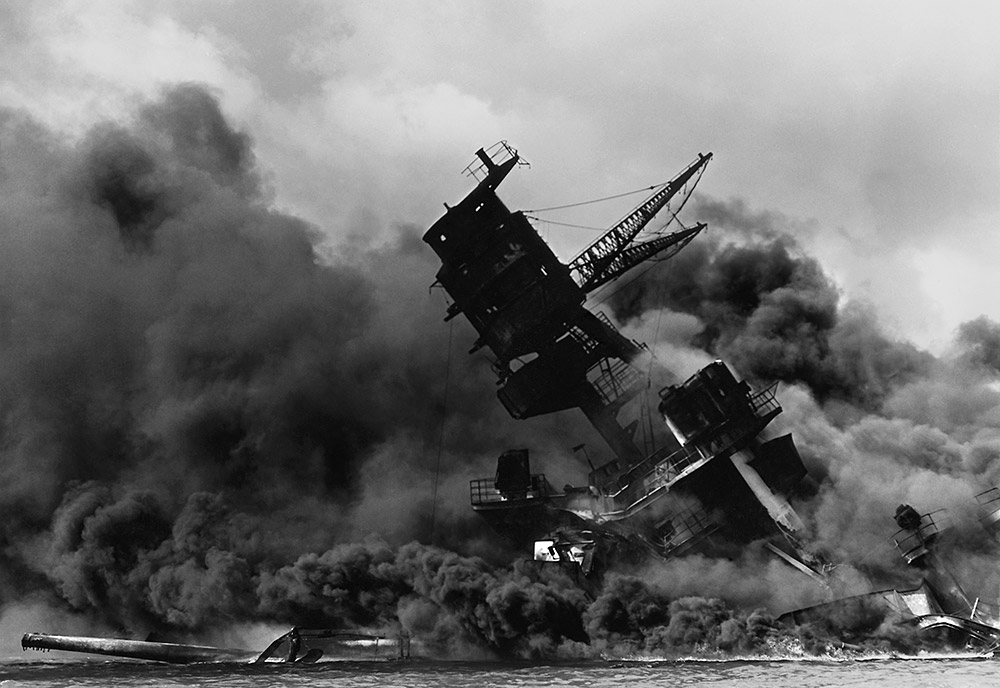 Black and white photo of the USS Arizona aflame in Pearl Harbor