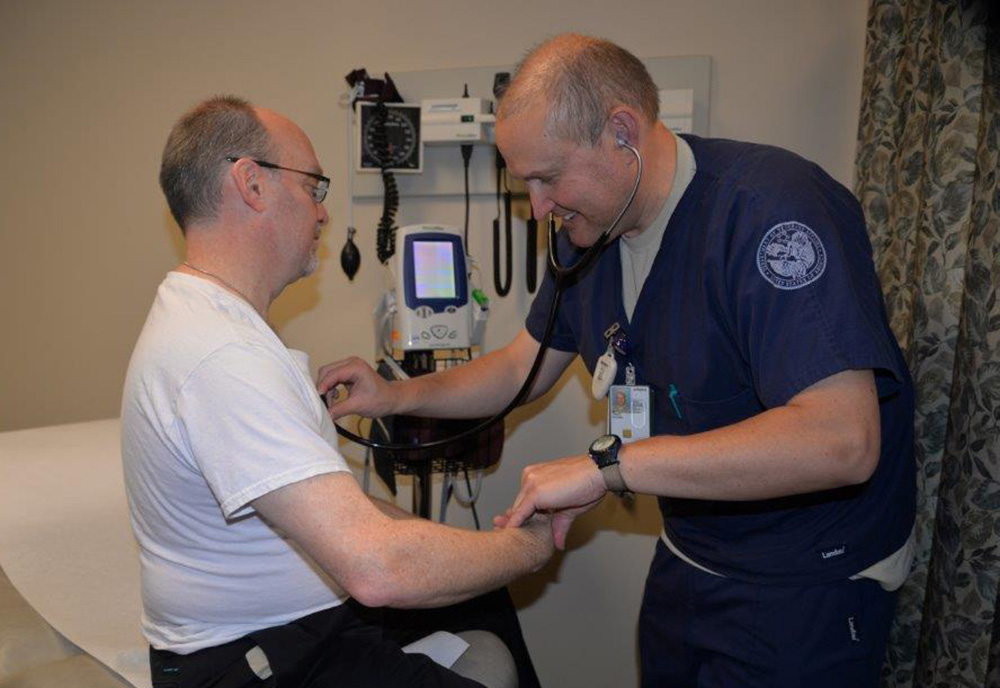 VA nurse Mike Twigg uses a stethoscope to examine a Veteran patient