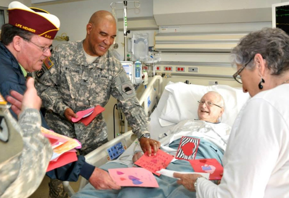 Male Veteran in inpatient care receiving Valentines cards from volunteers and visitors