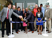 Several adults and a child cutting a ribbon in front of a health care clinic