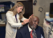 An audiologist installs a hearing aid for a Veteran patient