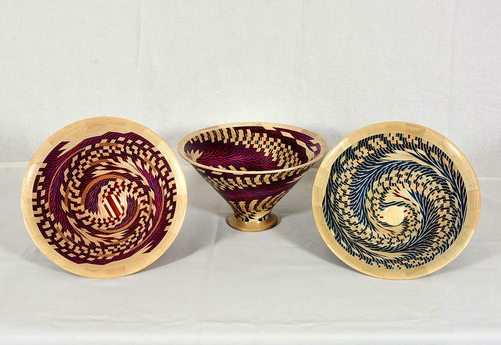 Three wooden bowls with colorful, intricate patterns on display