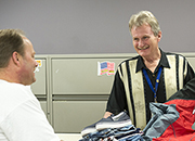  Image of a male volunteer handing out clothes to a male Veteran. 
