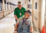 Image of a volunteer pushing a patient in a wheelchair. 
