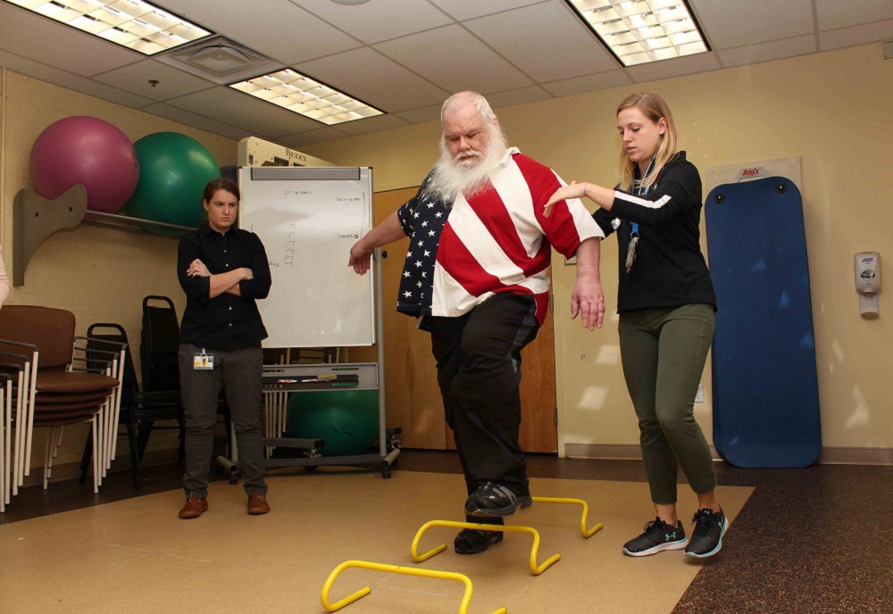 Army Veteran Gary Lucas navigates a hurdle exercise with the help of study coordinator Lydia Paden.