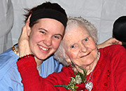 Elderly woman in a wheelchair hugs a young woman