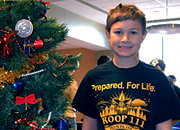 Boyscout next to a decorated tree