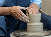 Hands forming clay on a potter's wheel