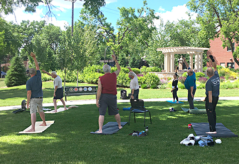 Veterans practice yoga poses outside in a garden