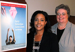 Two women standing by a poster about breast cancer