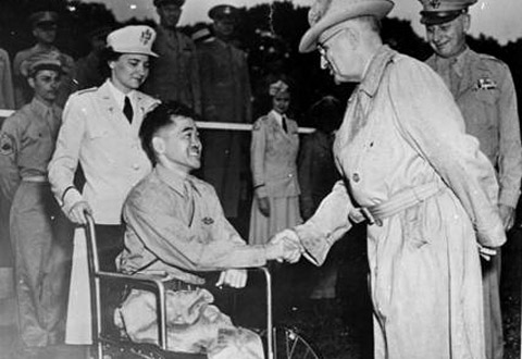 Black and white photo of President Truman shaking the hand of a man in a wheelchair