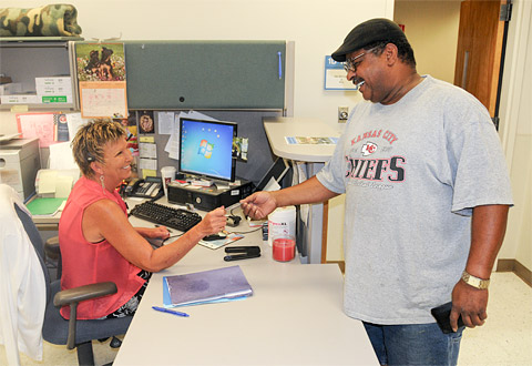Man shows his ID card to a woman at a desk
