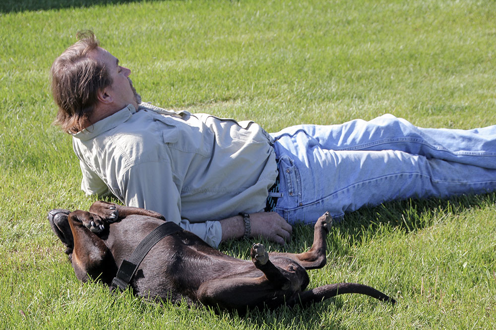 Veteran with a dog laying on the grass