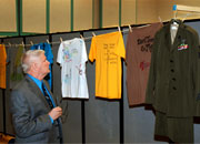 man looks at display of decorated shirts and a military uniform