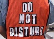 back of a woman wearing a bright orange vest with the words 