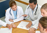 A group of medical professionals conduct a discussion while sitting at a table.