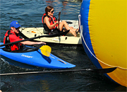 People in kayaks play with giant beach ball