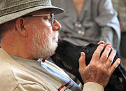 elderly man caressing a black Labrador retriever