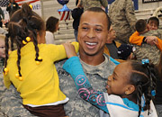 Returning soldier smiles and holds his daughters