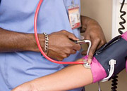 Man in scrubs checking a woman’s blood pressure