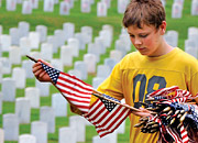 A boy carries flags through a Veteran cemetery