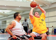 Three Veterans in wheelchairs play basketball