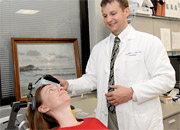 Woman in reclining position awaiting TMS Therapy, with male doctor in background