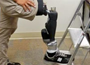 Veteran standing sideways, one foot on the ground, the other, a bionic leg, resting on a stepladder