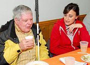 Man with a cane enjoys a meal nd visits with the woman beside him
