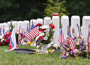woman sitting by grave markers decorated with flags and flowers