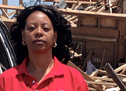 A woman stands in front of tornado damage