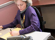 A woman in a wheelchair is on the telephone at her desk