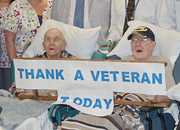 Two elderly Veterans hold a sign that says Thank a Veteran Today