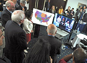 People congregate around a map of the US and a large video screen