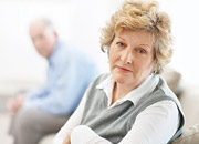 A senior woman caregiver with a man in the background