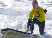 A man with one arm rides a wave on his surf board