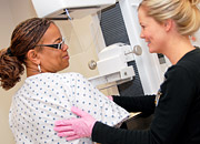 A health care worker helps a woman at a mammography machine