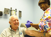 A Veteran smiles as a nurse prepares his flu vaccination