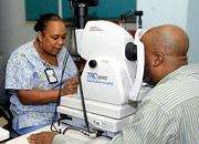 A woman tech operates a device to examine a man's eyes