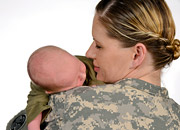 A woman in military uniform holds an infant