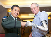 A colonel and Veteran bump together fist and prosthetic hand