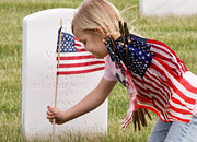 A girl places a flag at the grave of a soldier