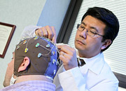 A doctor places electrodes on the head of a man