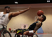 A man in a wheelchair tries to shoot a basket while another man in a wheelchair reaches to block