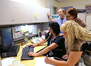 Four health care workers crowd around a computer