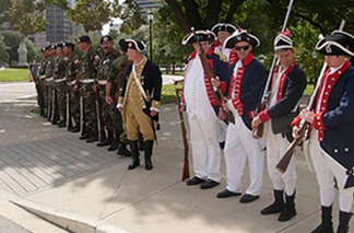 Current day soldiers along with reenactors dressed in revolutionary war uniforms