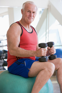 man sitting on exercise ball using hand weights