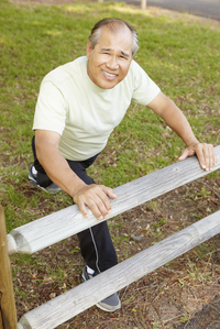 man stretching against split-rail fence